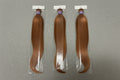 Three packages of blonde hair extensions on a gray background